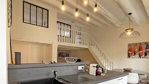 Una cucina moderna con un'isola grande, mobili bianchi e soffitto in legno.