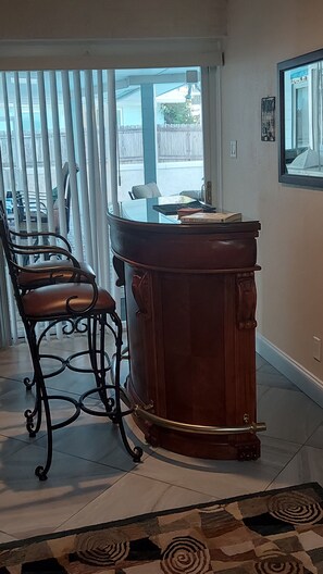 A room with a glass-top table, a leather chair, a wooden cabinet, and a patterned rug. - PRIVATE HOME Private pool, steps to the BEACH (Port Orange)
