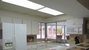 Eine Küche mit Kühlschrank, Mikrowelle und einer großen Kochinsel mit Stühlen.