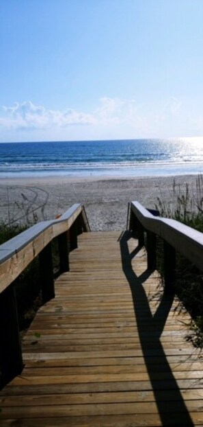 A wooden boardwalk leading to a beach with the ocean in the background. - PRIVATE HOME Private pool, steps to the BEACH (Port Orange)
