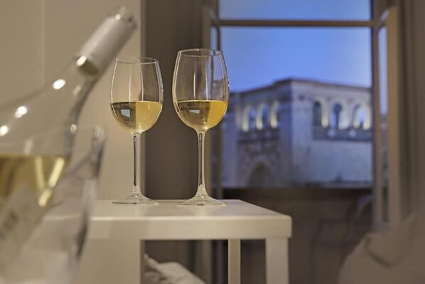 Two wine glasses on a white table with a view of a building through a window.