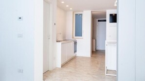Una cocina moderna con armarios blancos, horno empotrado y ventana sobre el fregadero.