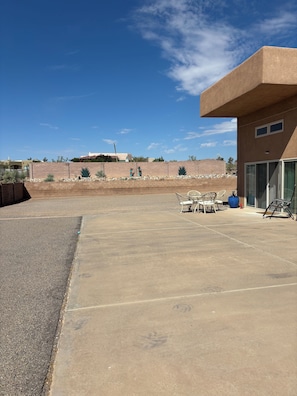 Une terrasse aménagée avec du mobilier d’extérieur, un ciel dégagé et une vue lointaine sur un paysage désertique.