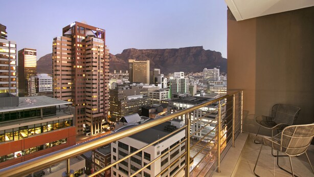 Varanda com vista para a cidade, incluindo edifícios altos e uma montanha ao fundo.