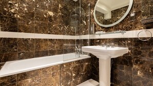 A bathroom with a bathtub, a sink, and a shower. - Cockspur Street by onefinestay (London)