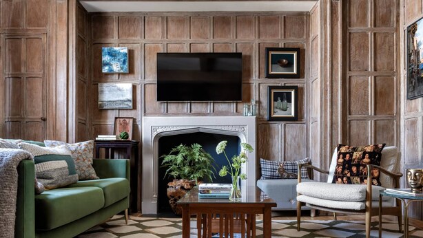 A living room with a fireplace, a green sofa, a wooden coffee table, and a television mounted on the wall. - Cockspur Street by onefinestay (London)