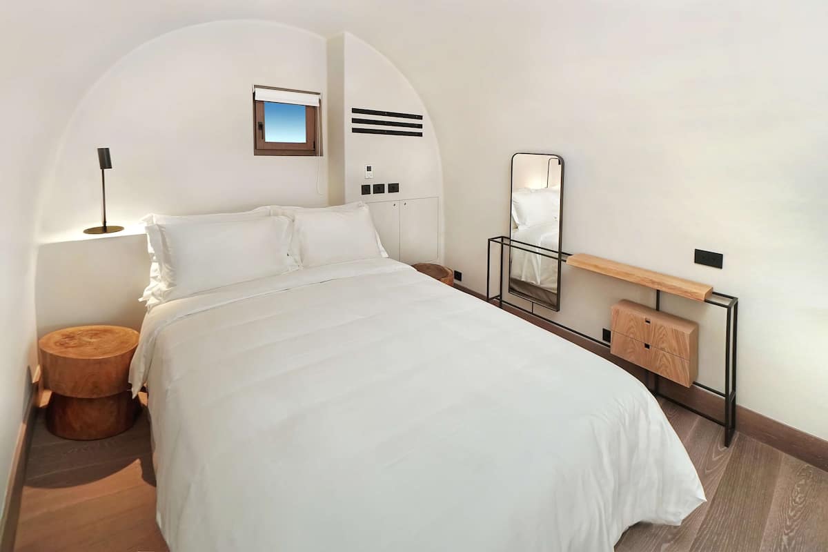 Relax in a serene space with a large bed and a wall-mounted mirror.