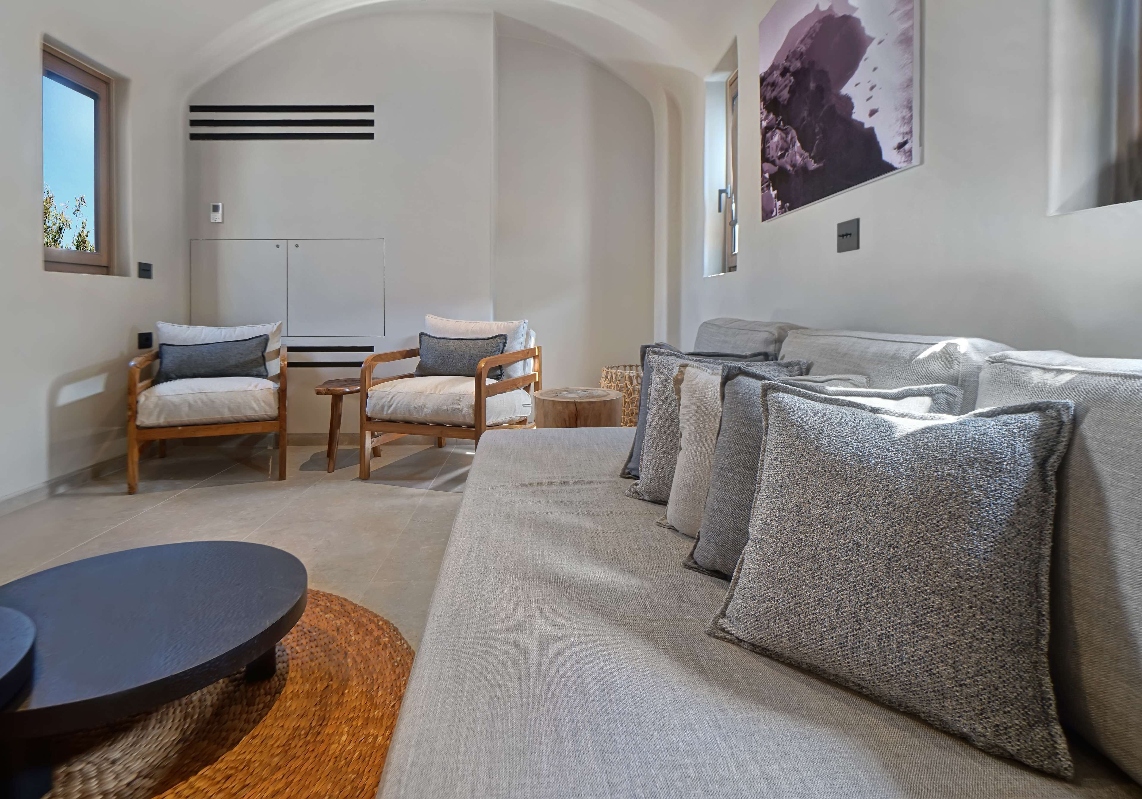 A modern living room with a sofa, two armchairs, a coffee table, and a large window.