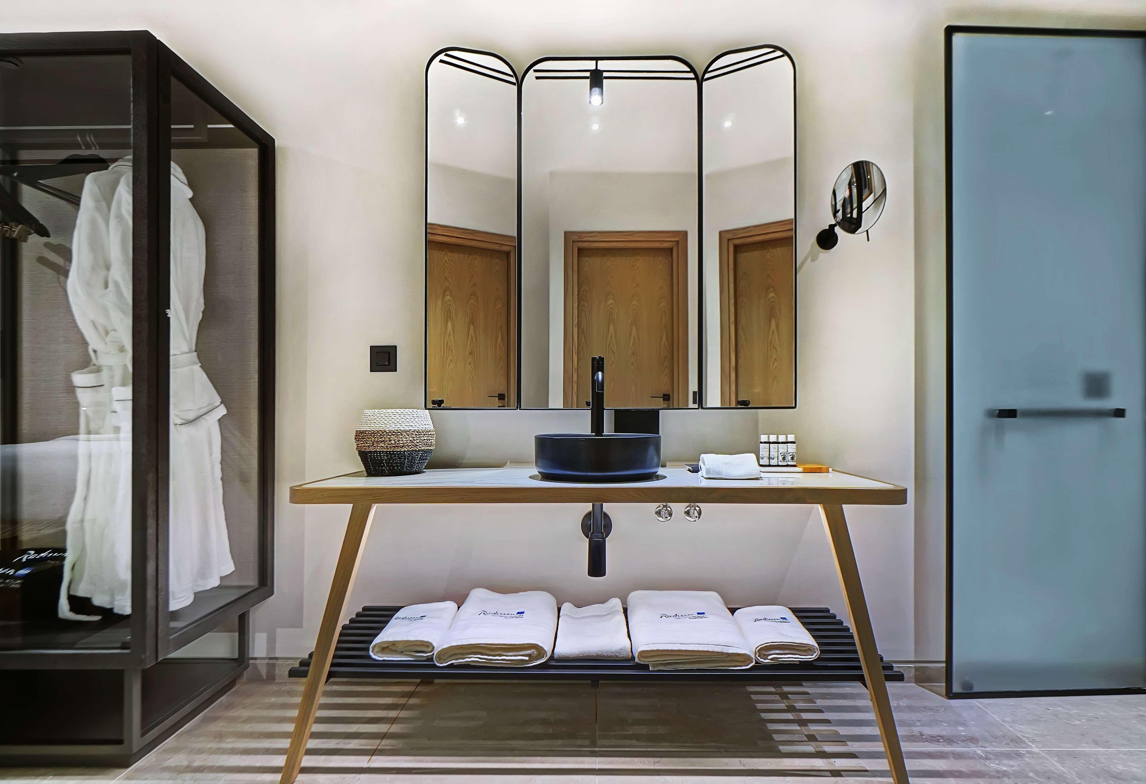 Une salle de bain moderne avec un meuble-lavabo, un grand miroir et un porte-serviettes intégré.