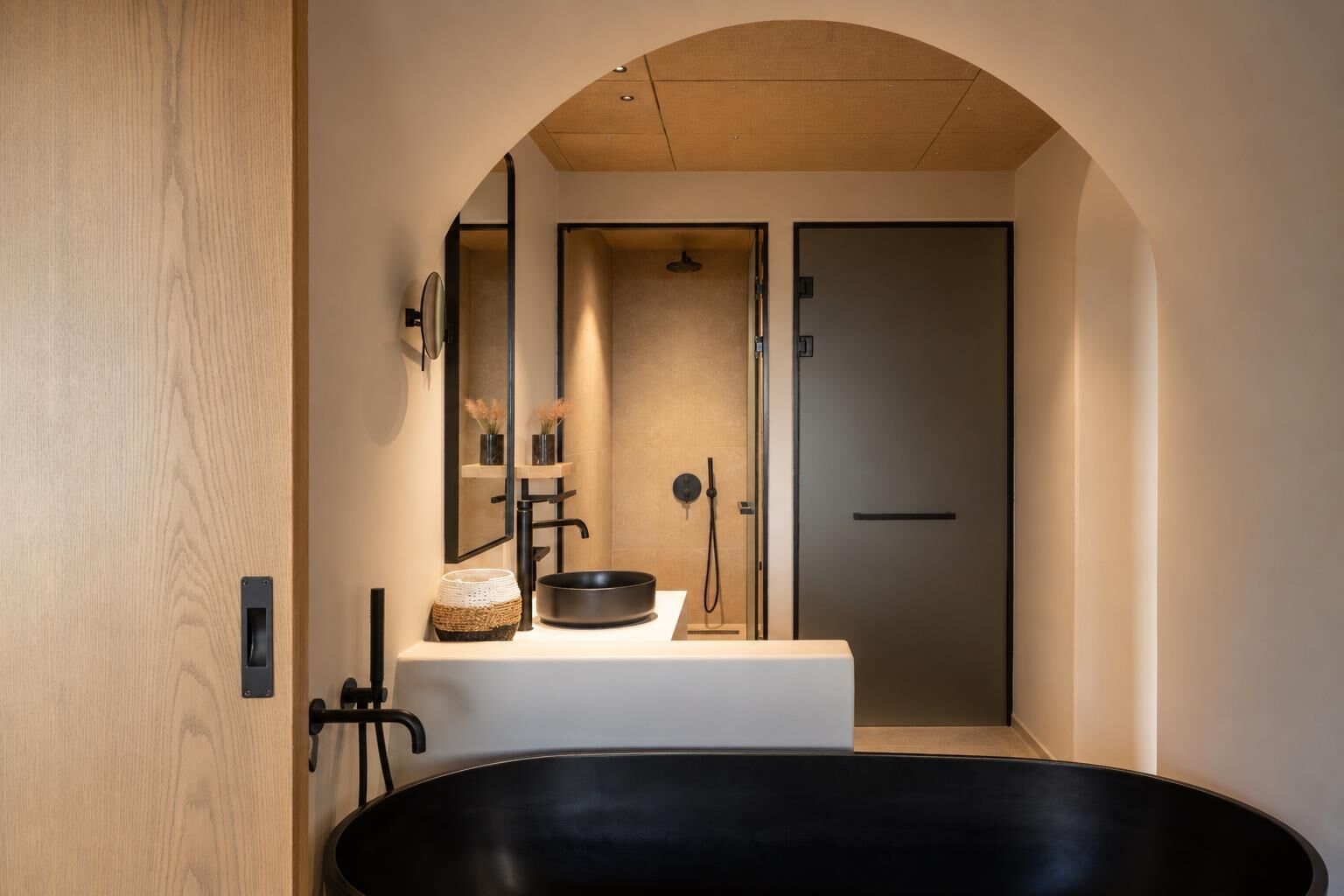 Un baño moderno con una bañera independiente, un espejo grande y una zona de lavamanos minimalista.