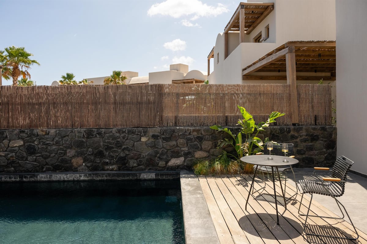 A pool area with a stone wall, wooden deck, and outdoor seating.
