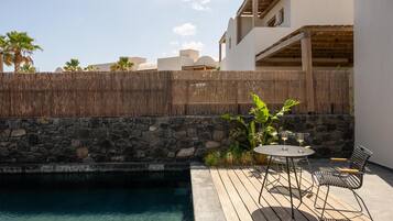 A pool area with a stone wall, wooden deck, and outdoor seating.