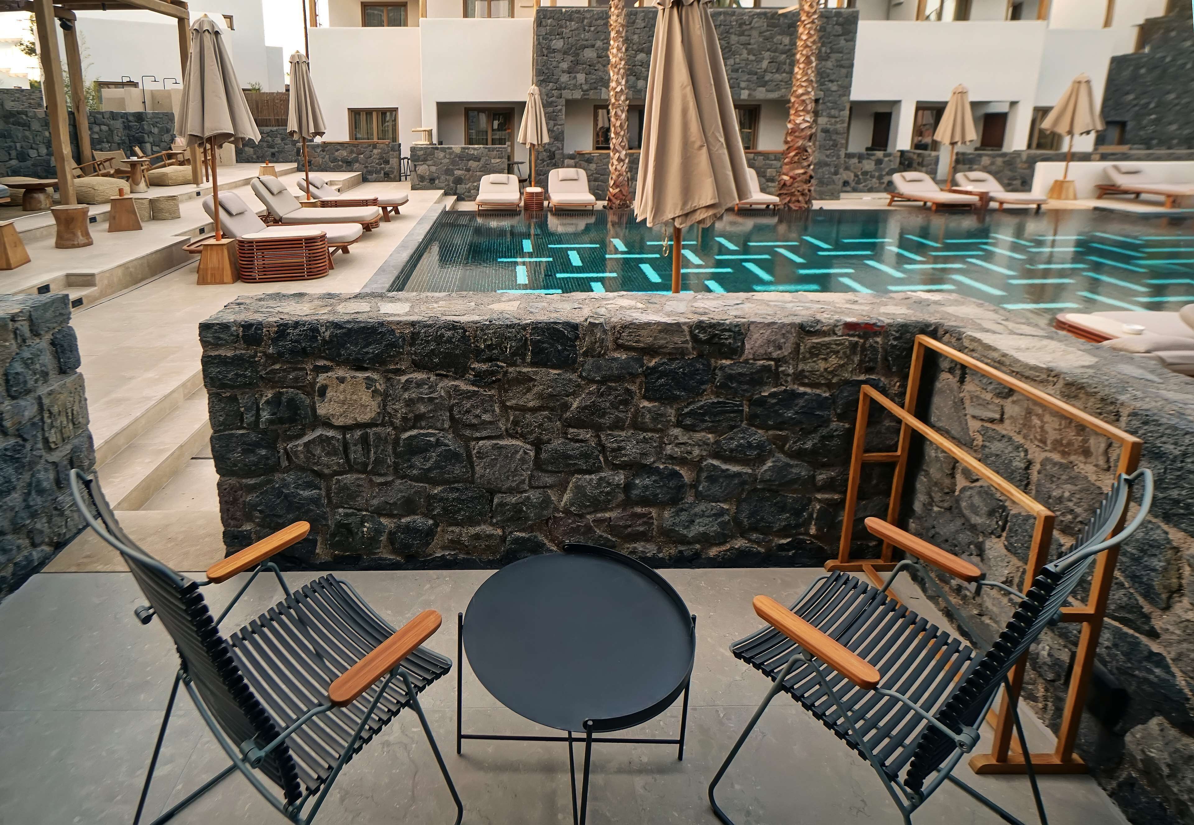 Un espace aménagé au bord de la piscine, avec des chaises longues, des parasols et une table.