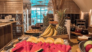 Un présentoir de fruits comprenant différents types de fruits, notamment des pastèques, des ananas et des bananes.