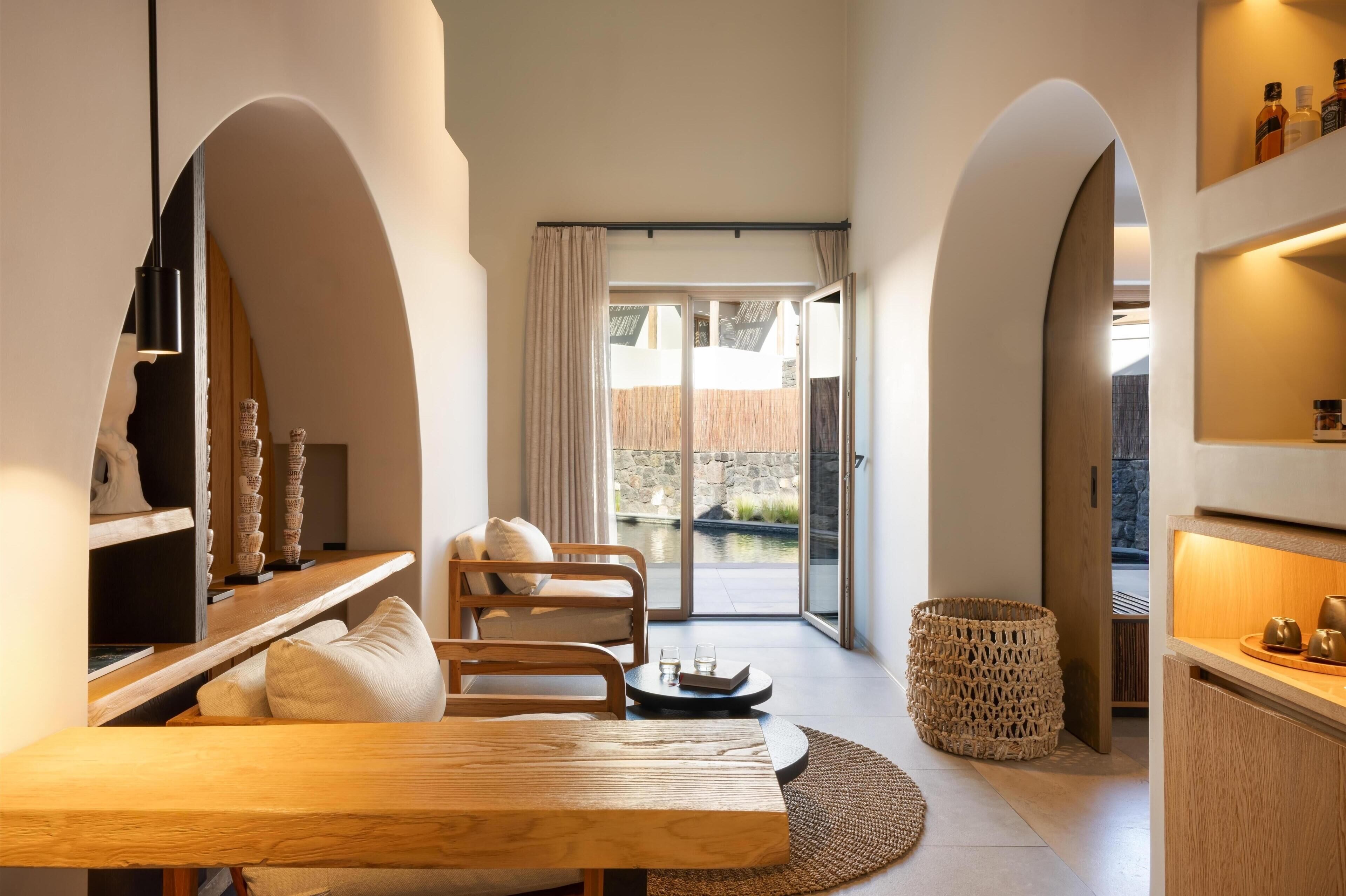 Um interior moderno com uma mesa de jantar de madeira, um sofá e vista para uma área externa através de uma porta de vidro.