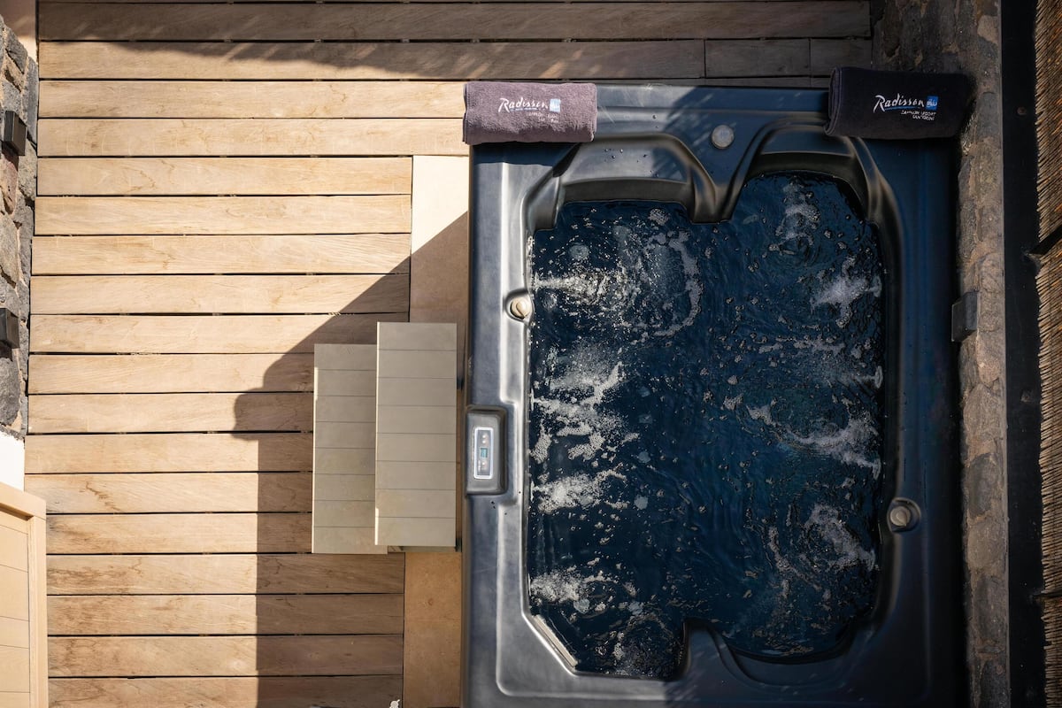 A spa tub with a control panel, a towel, and a wooden wall.