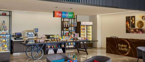 A modern cafe with a 'the market' sign, a 'Grab n' Go' refrigerator, and a 'huber & holly' counter.