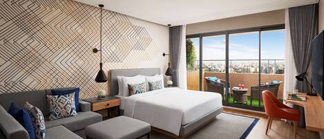 Una habitación de hotel moderna con una cama grande, un sofá, un comedor y un balcón con vista a la ciudad.