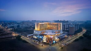 A multi-story hotel with a prominent central atrium, surrounded by parking and a street. - Hyatt Place Vadodara (Vadodara)