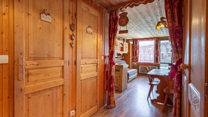 Een houten interieur met een eethoek, houten deuren en een klok aan de muur.