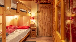 Een houten kamer met stapelbedden, een houten kledingkast en een klein nachtkastje met een lamp.