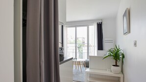 A modern, well-lit room with a large window, a white bench, a potted plant, and a visible door.