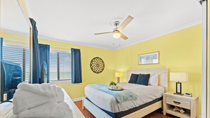 Ein Schlafzimmer mit Bett, Nachttisch, Lampe und Deckenventilator.