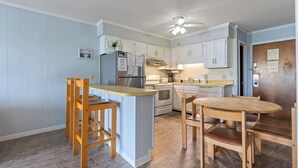 A kitchen with wooden chairs, a wooden table, a refrigerator, and a stove.