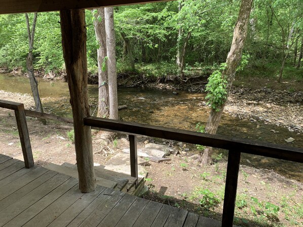 A wooden deck overlooking a forested area with a stream.