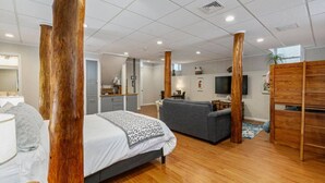 A modern bedroom with a large bed, a grey sofa, and wooden pillars. - Next to Boston & Beach, King Beds, Free Parking+EV (Quincy)