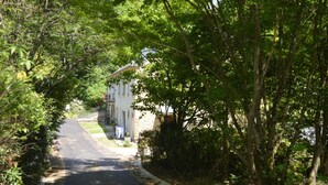 Una strada stretta costeggiata da alberi e un edificio con un balcone.