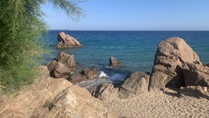 Eine felsige Küstenlinie mit großen Felsen und blauem, klarem Meer.