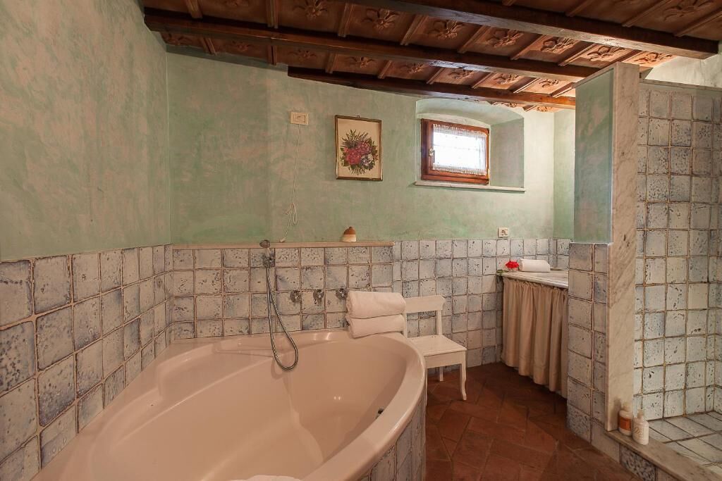 A bathroom with a freestanding bathtub, a small vanity with a mirror, and a window above the sink.