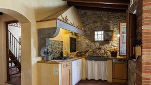 A compact kitchen with a stone wall, a small island, and a window above the sink. - Lovely Apartment with private patio and garden (Comune di Sesto Fiorentino)
