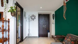 A living room with a green wall, a wooden floor, a sofa, a coffee table, and a door leading to another room.