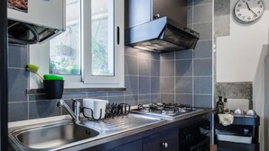A modern kitchen with a stainless steel sink, a gas stove, and a black range hood.