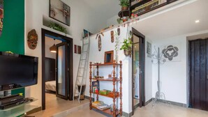 A living room with a TV, a bookshelf, and a ladder.