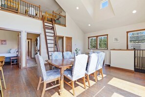 Un vaste espace de vie de style loft comprenant un coin repas, une zone de couchage en mezzanine et une cuisine.