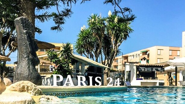 Un espace piscine agrémenté des mots « PARIS 24 » et de palmiers.