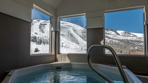 A hot tub with a view of a snowy mountain landscape through large windows. - Lodge at Mtn Village B148 | Ski-In/Out | Valley View | Washer/Dryer | Pool | Hot Tub (Park City)