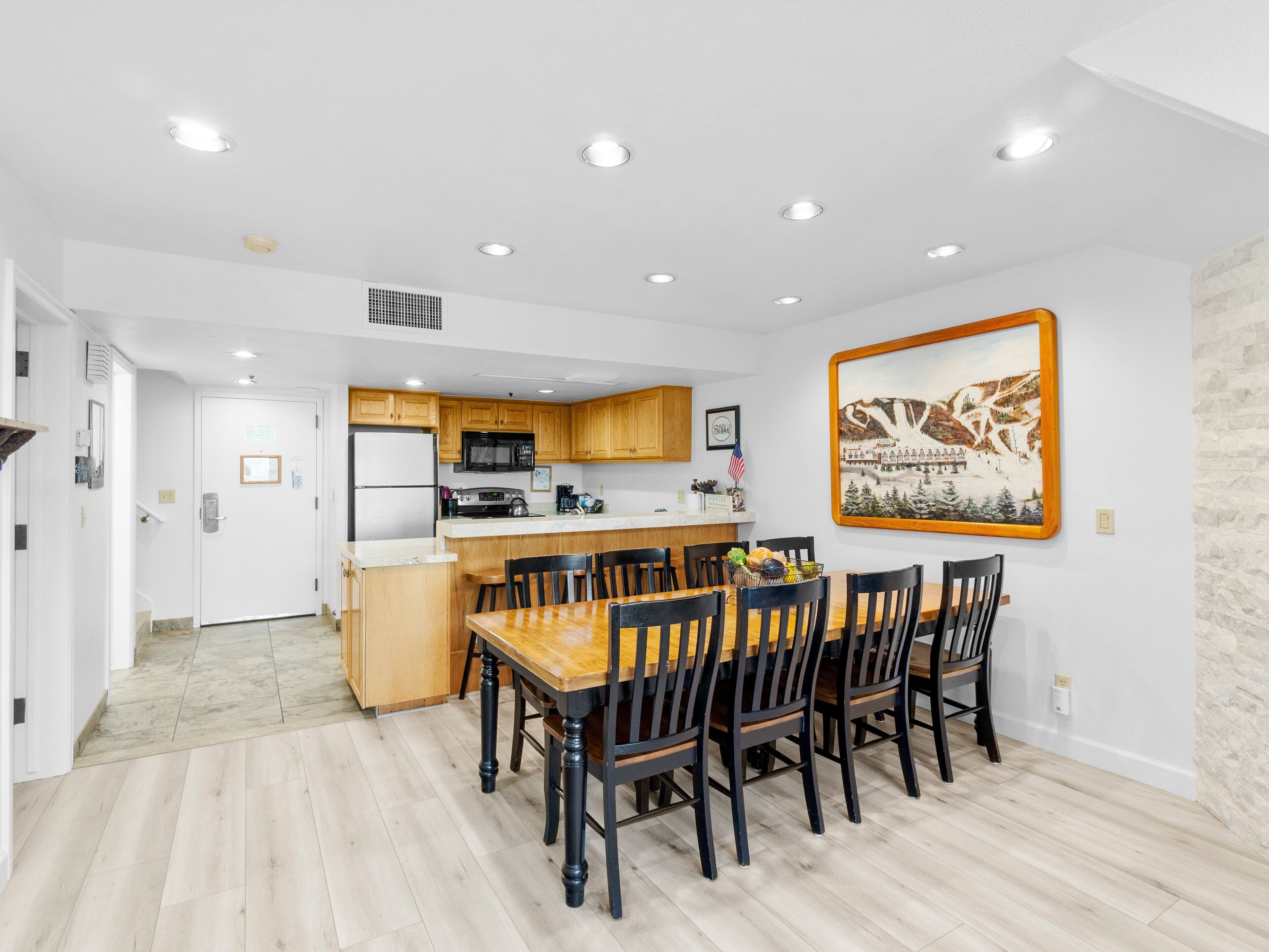 A modern kitchen with wooden cabinets, a central island, and a dining area with a wooden table and chairs.