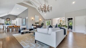 A spacious living area with a modern sofa, a dining table, and a kitchen in the background. - Newly Renovated, Modern home with pool, cathedral ceilings, open-floor... (Southampton)