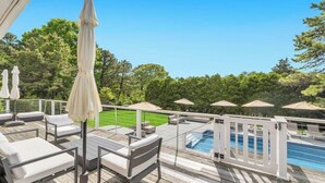 A poolside area with lounge chairs, umbrellas, and a view of a swimming pool. - Newly Renovated, Modern home with pool, cathedral ceilings, open-floor... (Southampton)