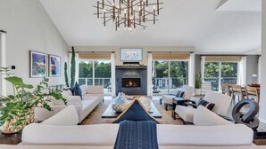A modern living room with a fireplace, white sofas, a coffee table, and large windows. - Newly Renovated, Modern home with pool, cathedral ceilings, open-floor... (Southampton)