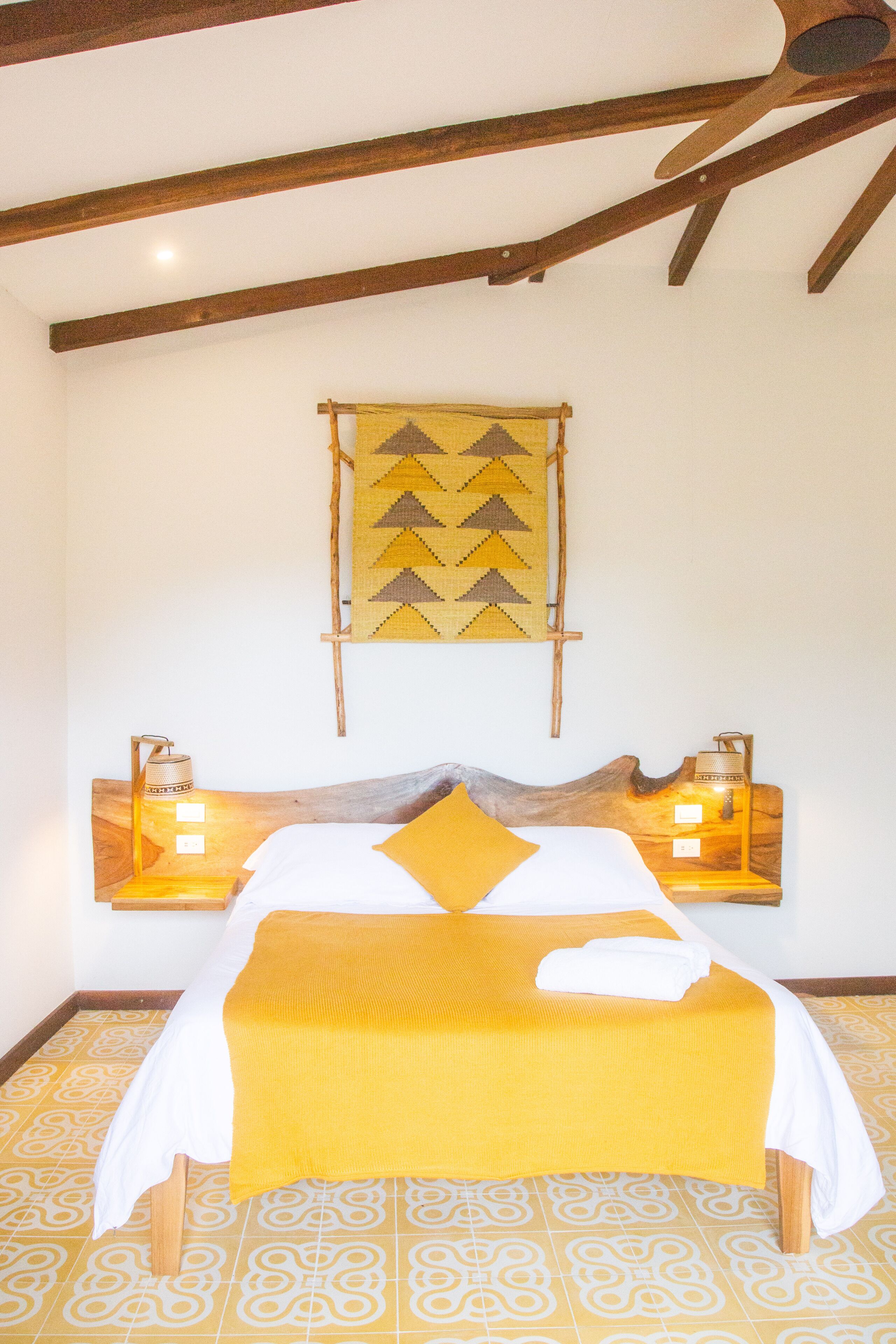 A bed with a wooden headboard, two bedside lamps, and a patterned floor.