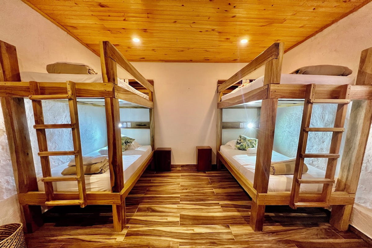 A room with two bunk beds, wooden flooring, and a wooden ceiling.