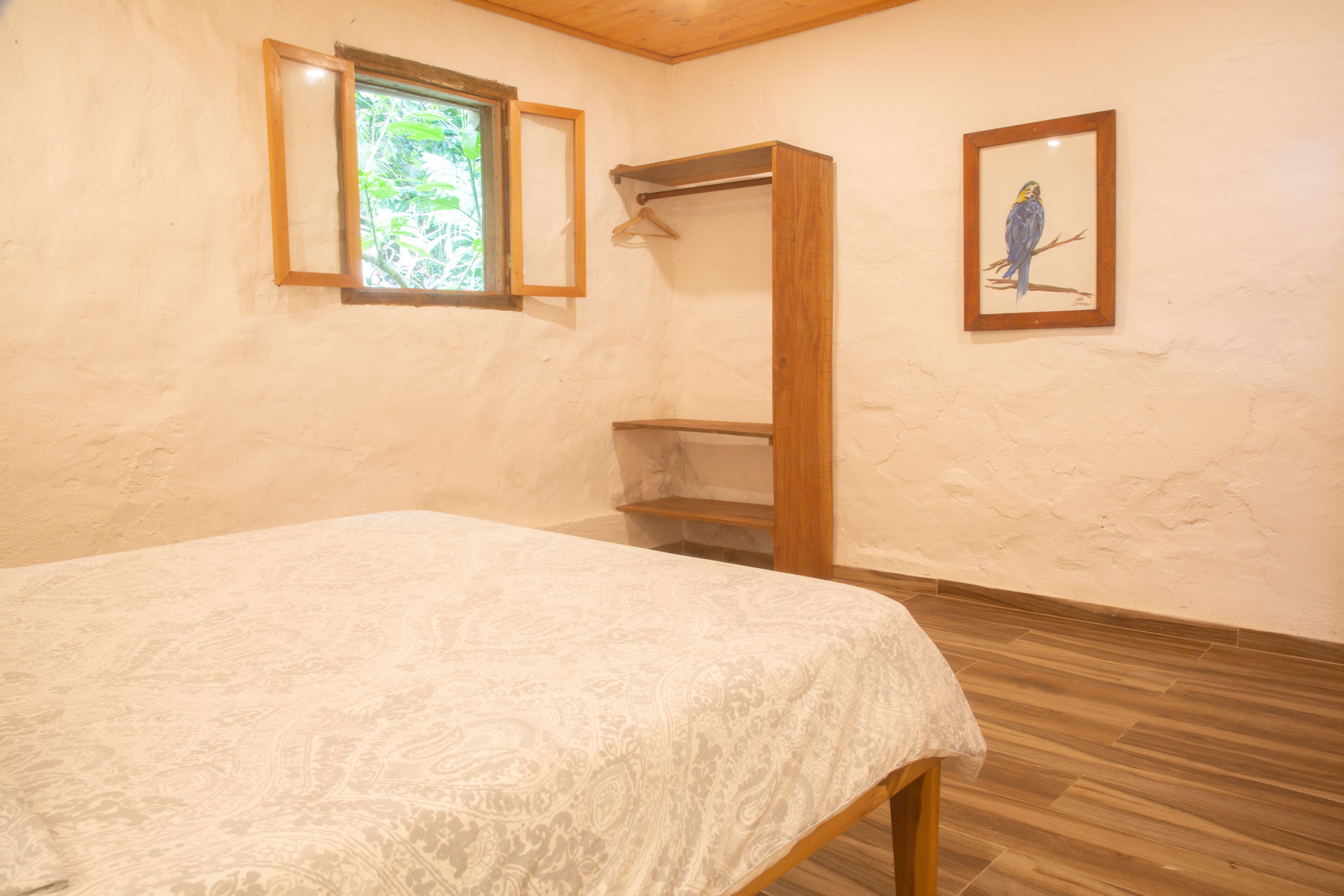 Un dormitorio con cama, un armario de madera, una ventana y un cuadro en la pared.