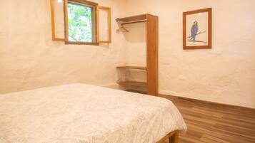 Un dormitorio con cama, un armario de madera, una ventana y un cuadro en la pared.