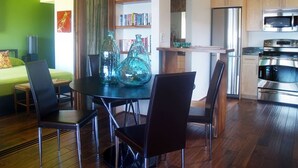 A modern living space with a dining area, kitchen, and a green accent wall. - B10: 1 bedroom, 3rd floor, oceanview (Princeville)