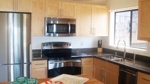 A kitchen with stainless steel appliances, wooden cabinets, a granite countertop, and a window. - B10: 1 bedroom, 3rd floor, oceanview (Princeville)